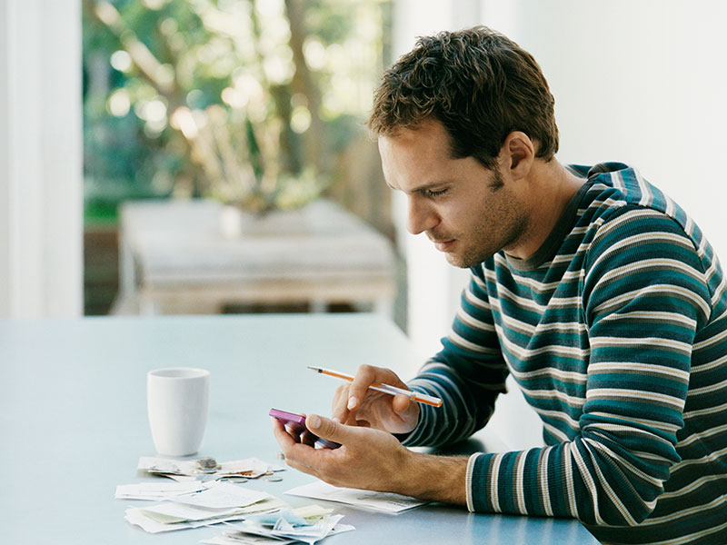Man Sitting at a Table Using a Calculator