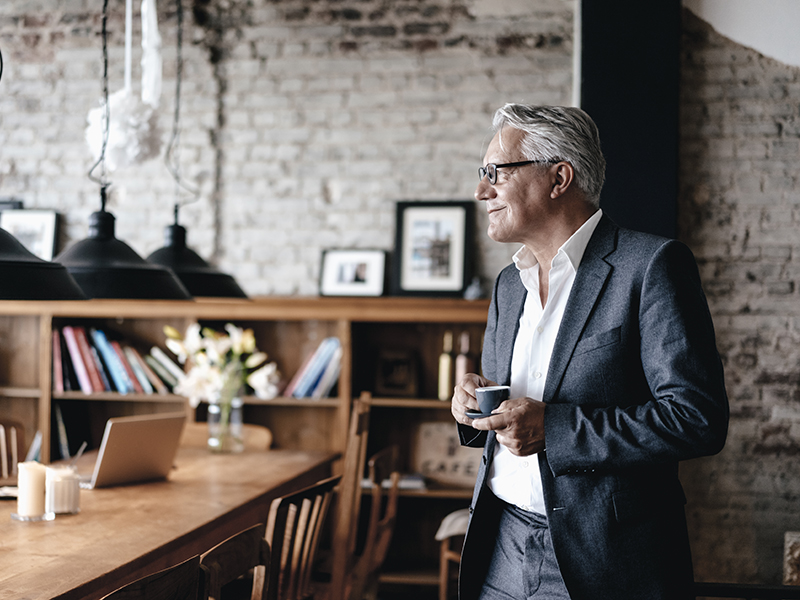 Senior businessman drinking coffee, smiling alternate text for this image