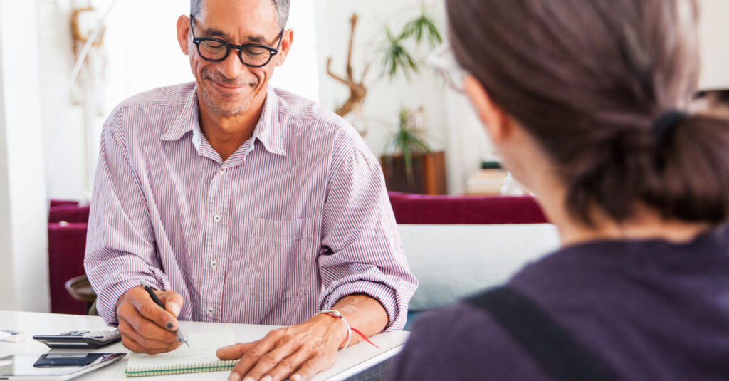 Financial advisor at his desk writing notes for his client.