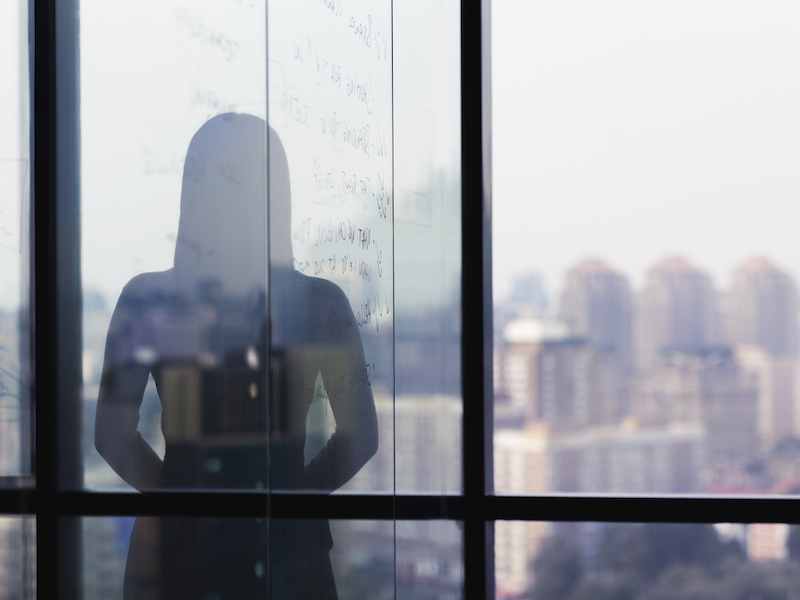 Silhouette shadow of woman looking at city from office