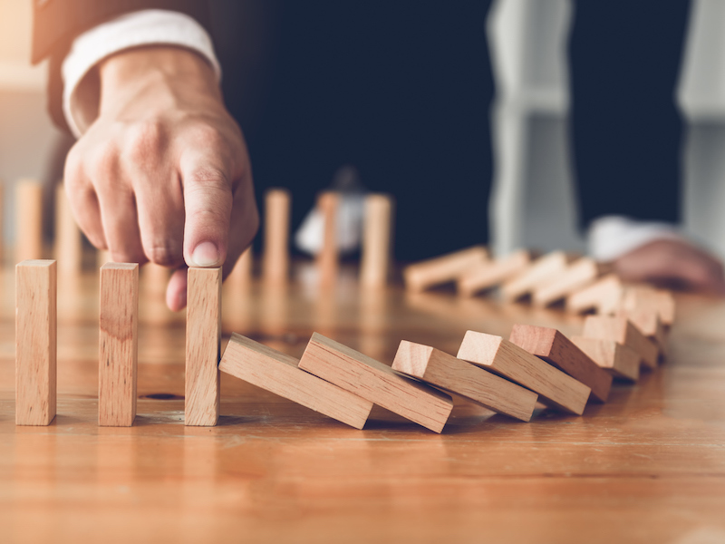 Man stopping line of dominoes from falling