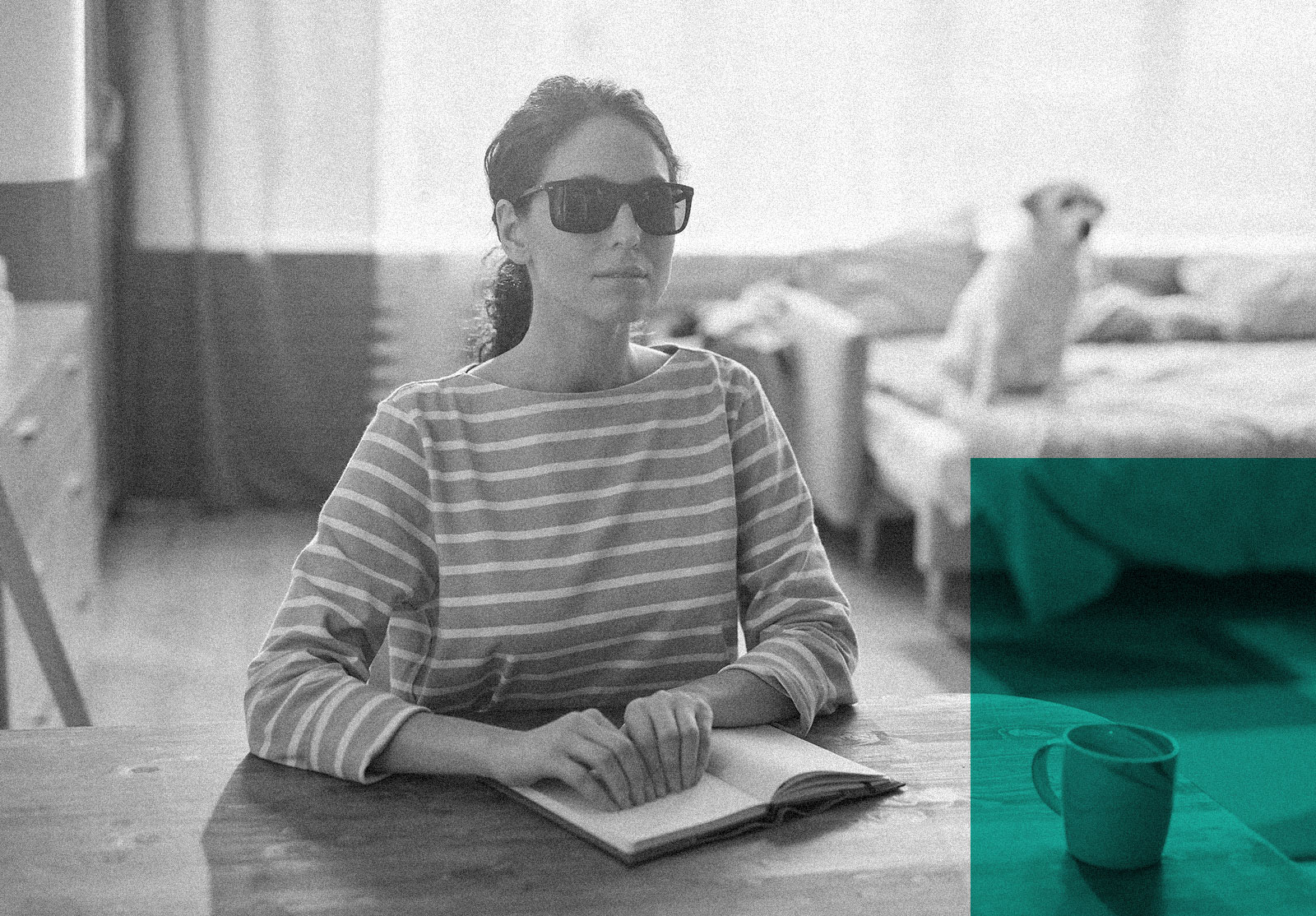 Blind woman reading a braille book with her dog in the background