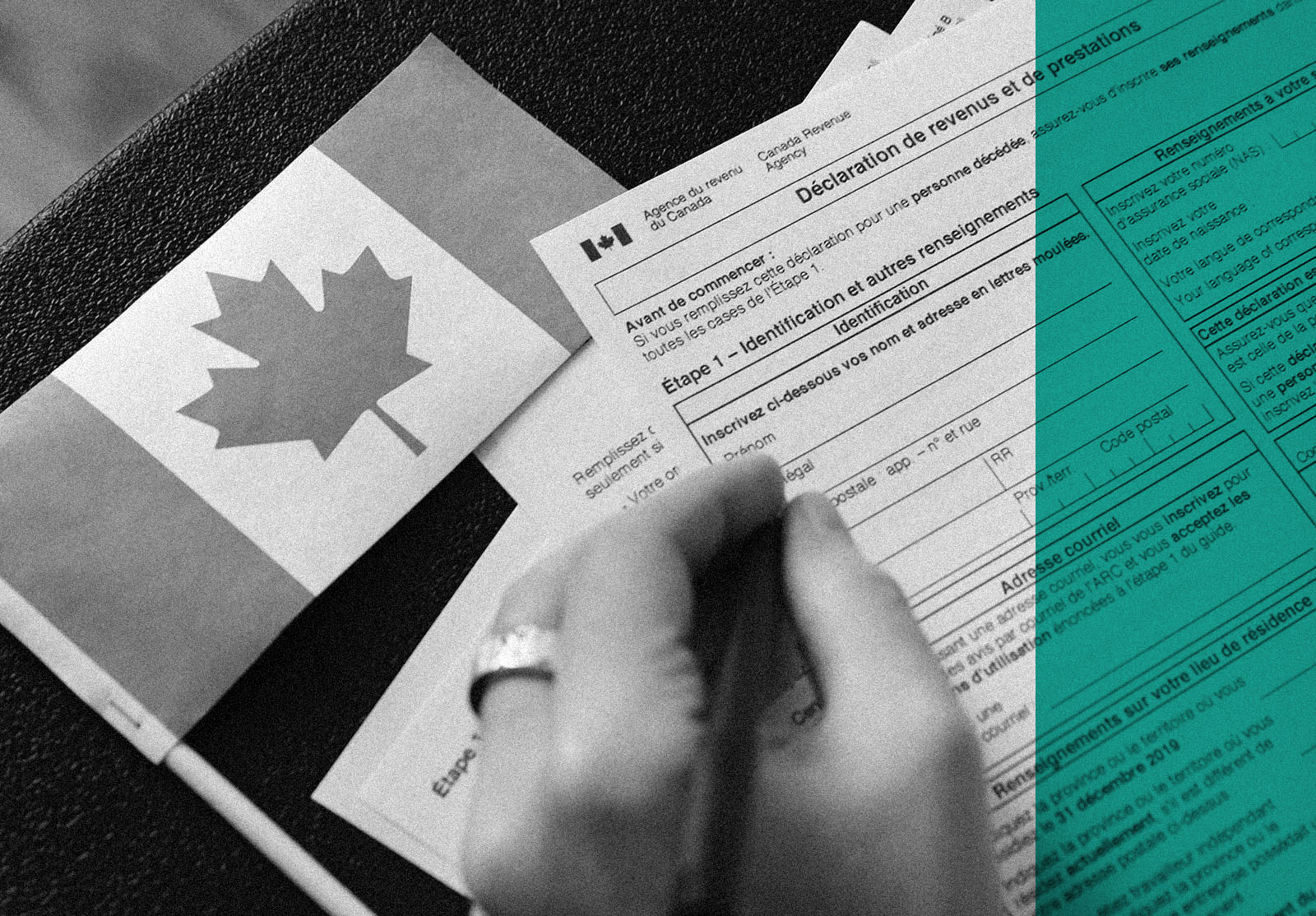 Man hand's filling canadian tax papers in French. Canadian flag on the table.