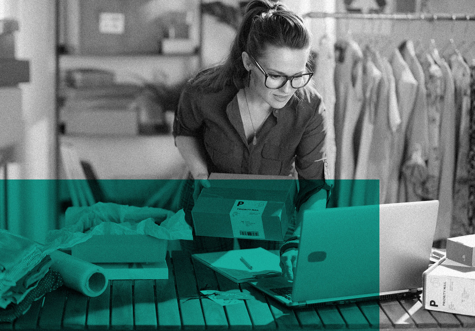 Middle aged woman with parcel using laptop in the office.