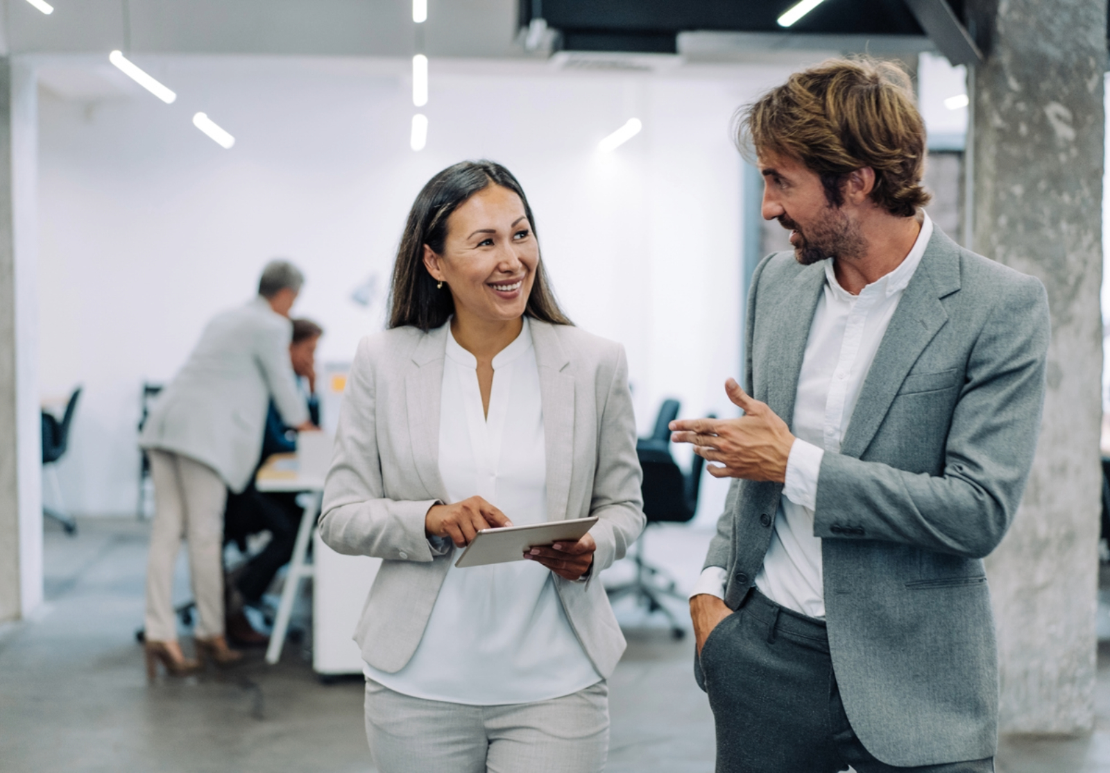 Shot of two coworkers having a discussion in modern office. Businessman and businesswoman in meeting using digital tablet and discussing business strategy.