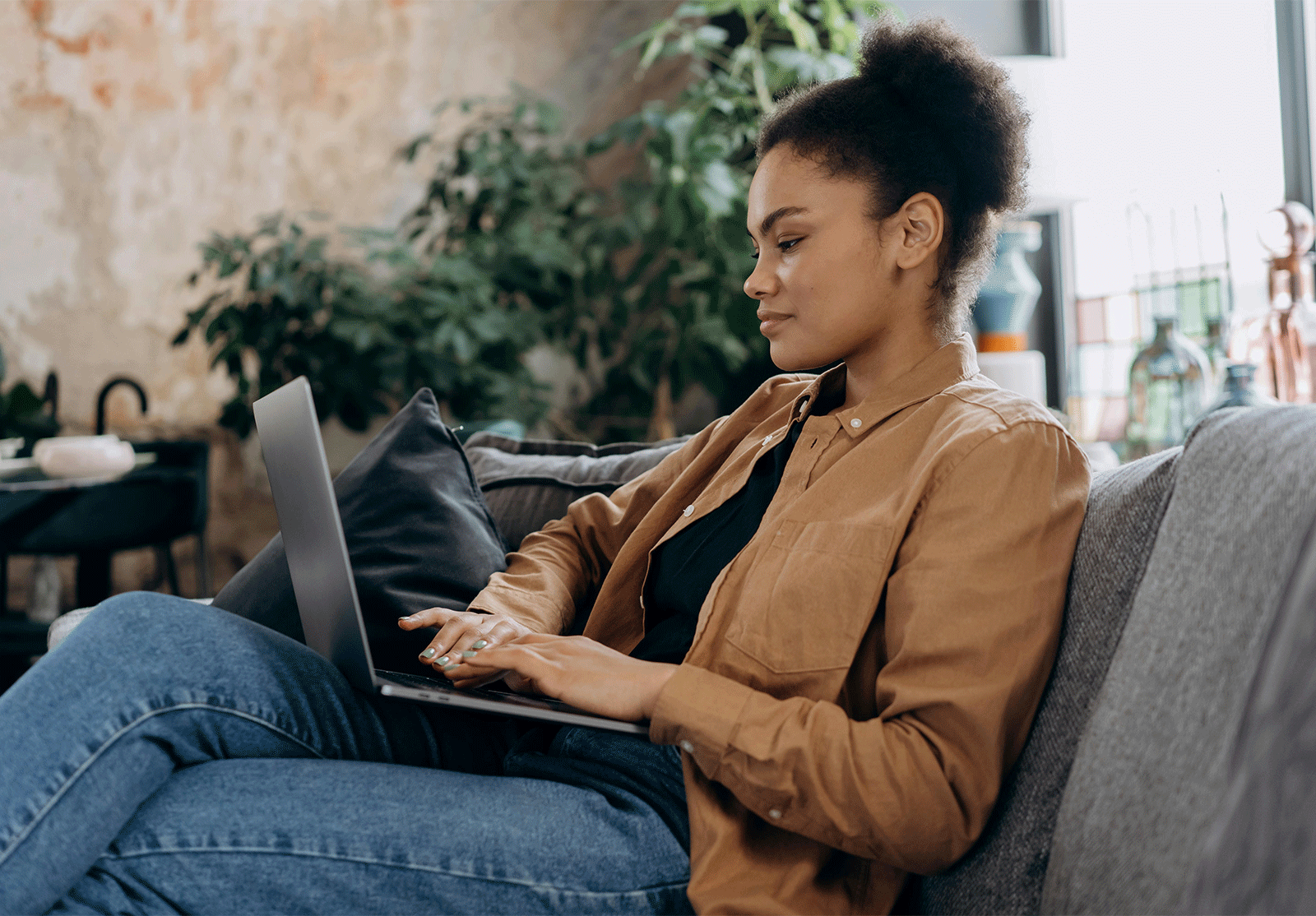 Woman sitting on a couch as she types on her laptop computer
