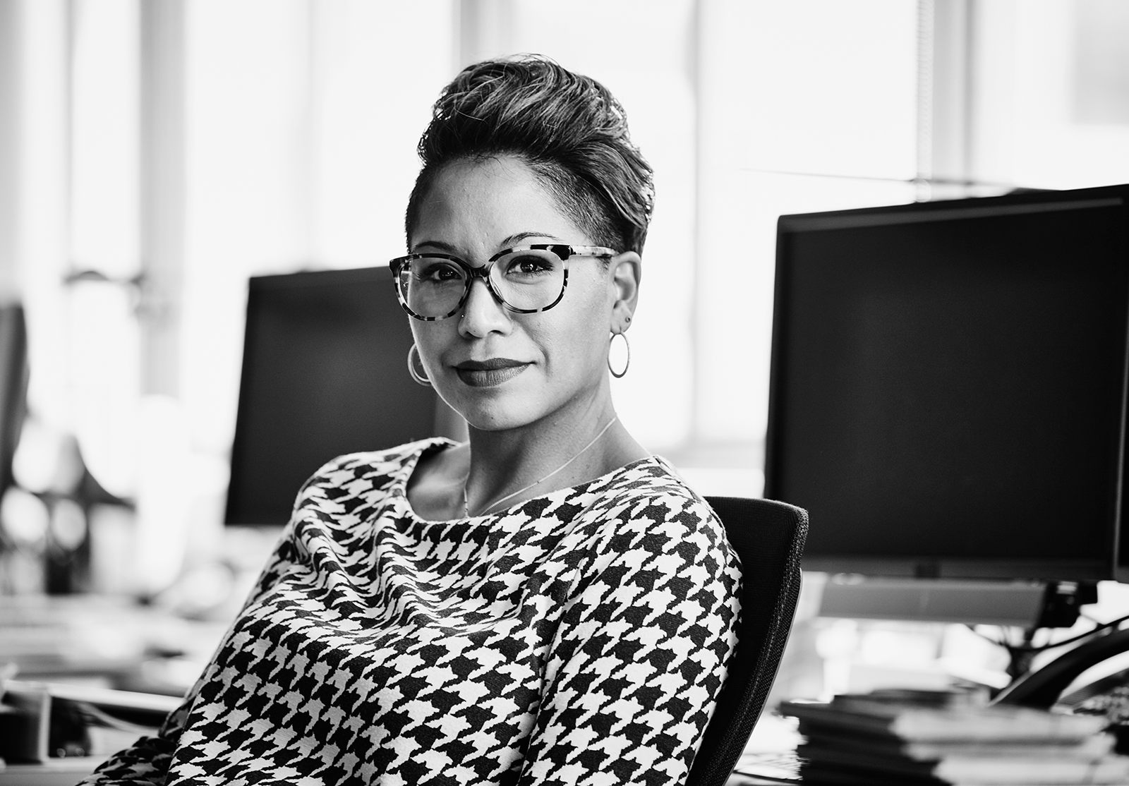 Smiling businesswoman seated at office workstation.