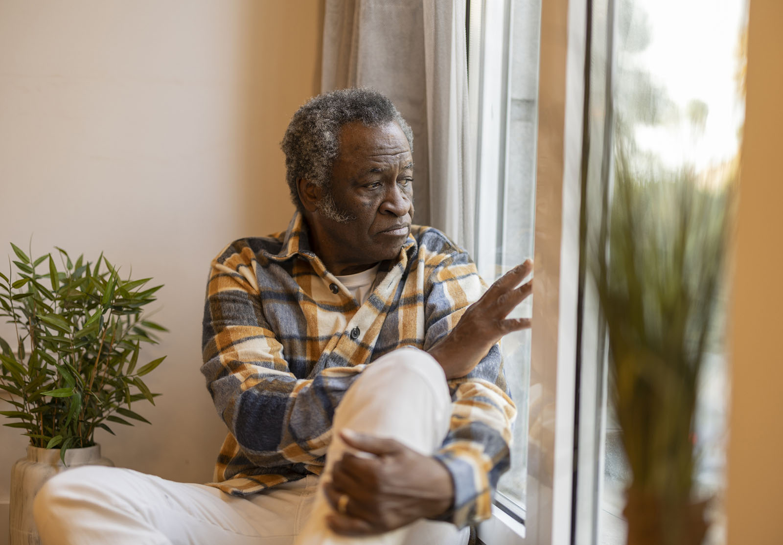 elderly pensioner at home sad looks out the window serious