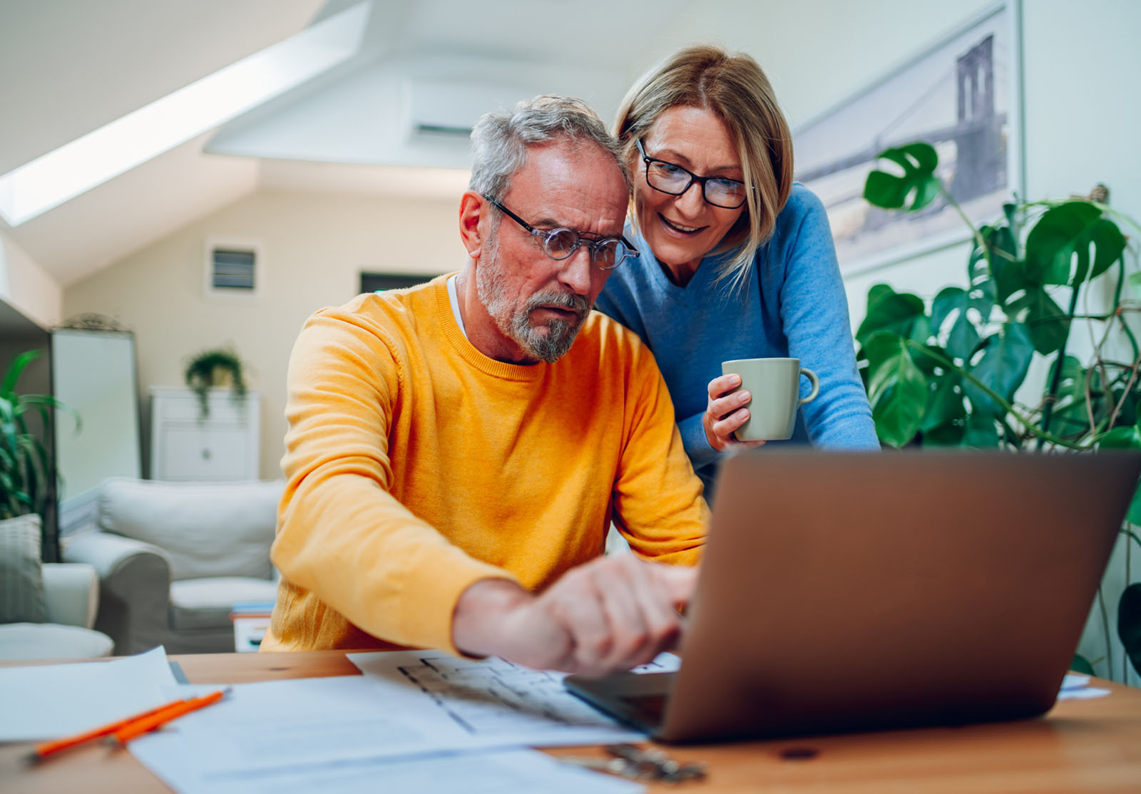 Senior middle aged happy couple using laptop together at home