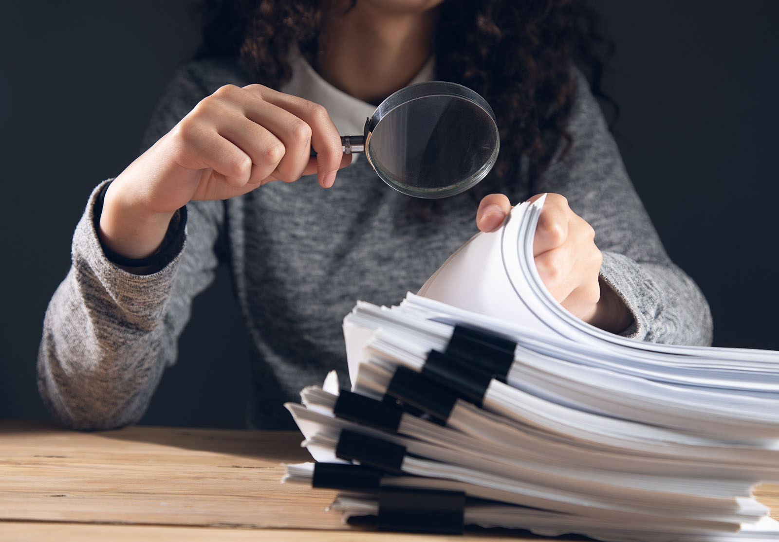 woman holding magnifying glass and documents