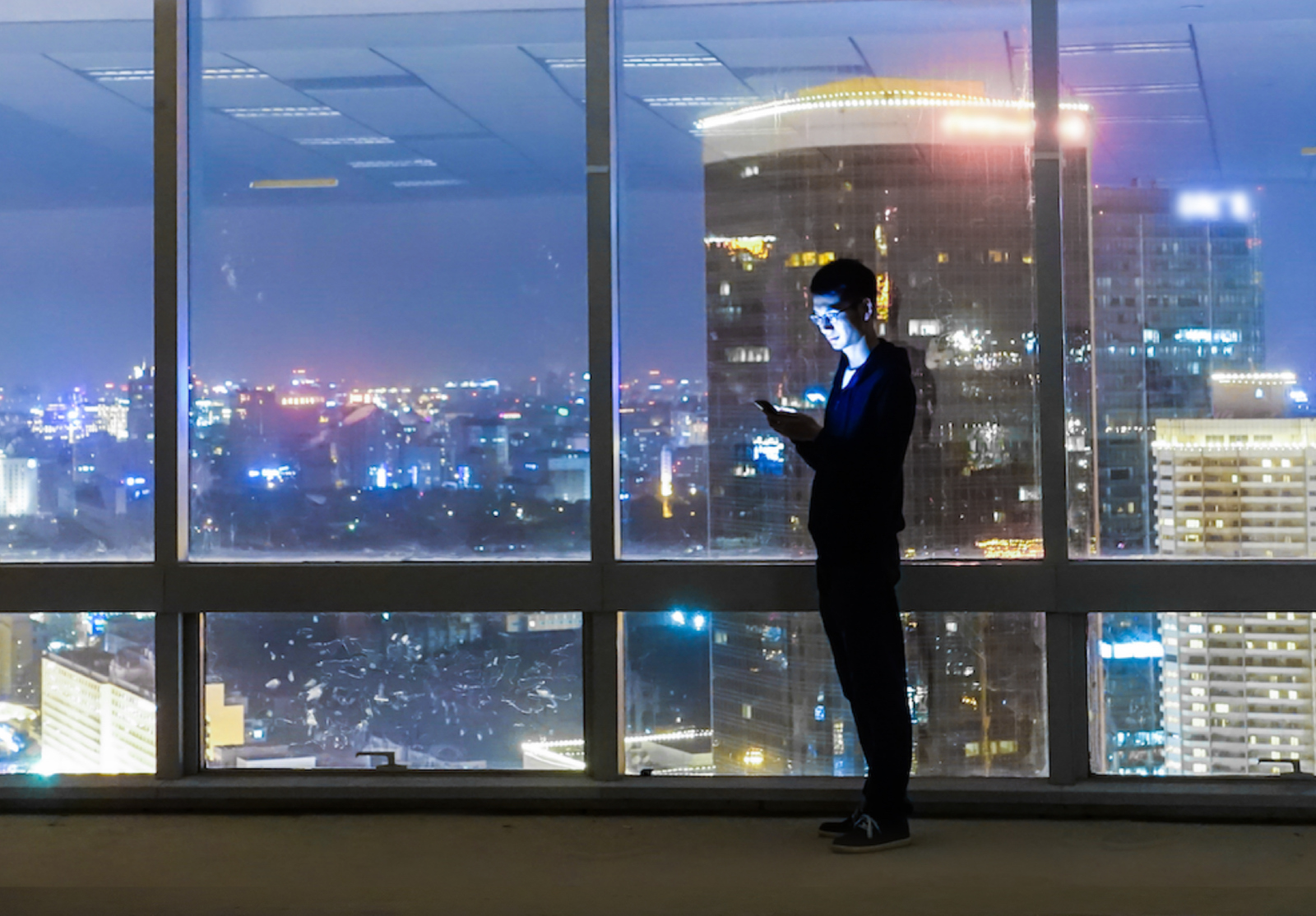 Man using phone at city night alternate text for this image