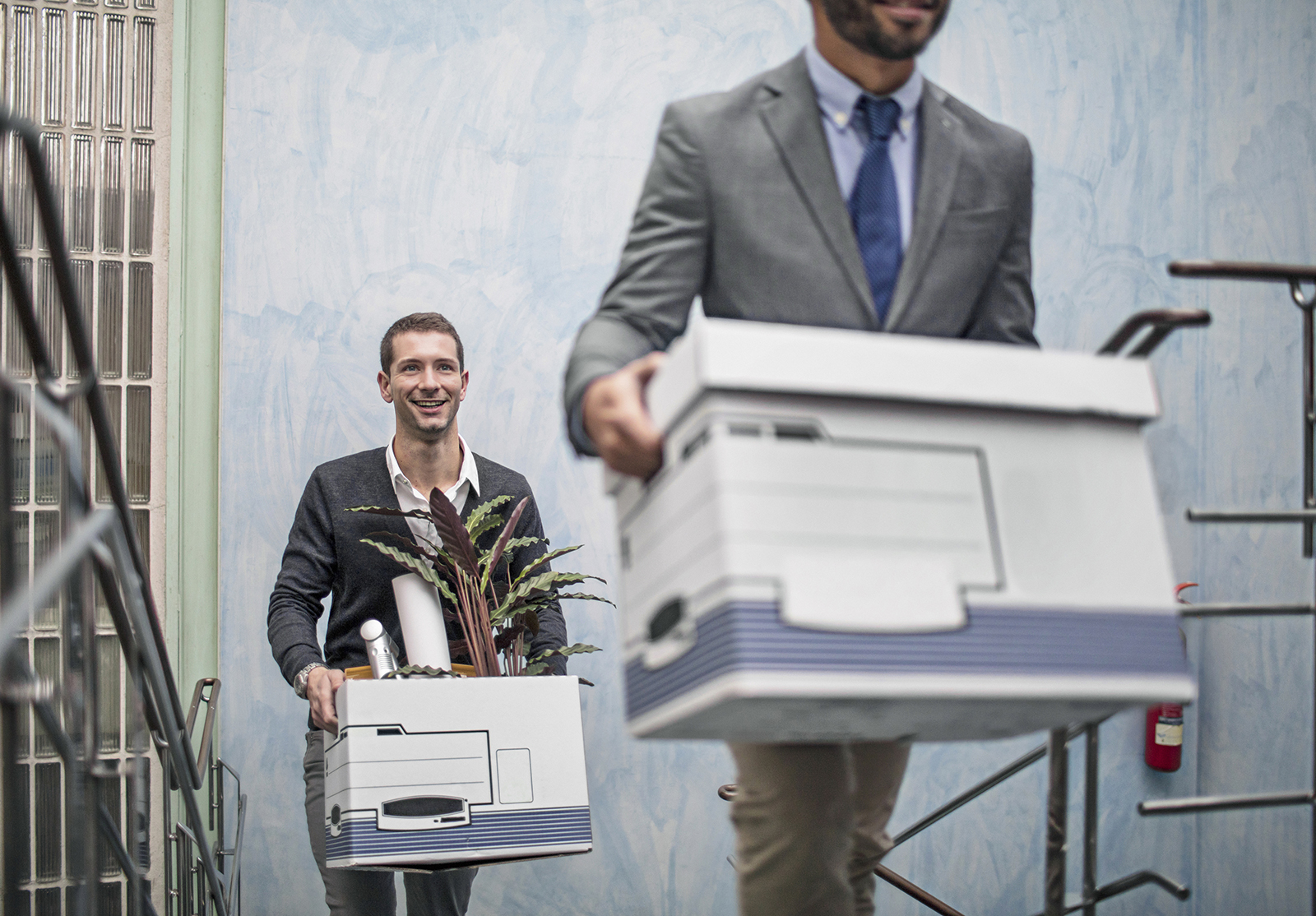 Businessmen with belongings on staircase in office