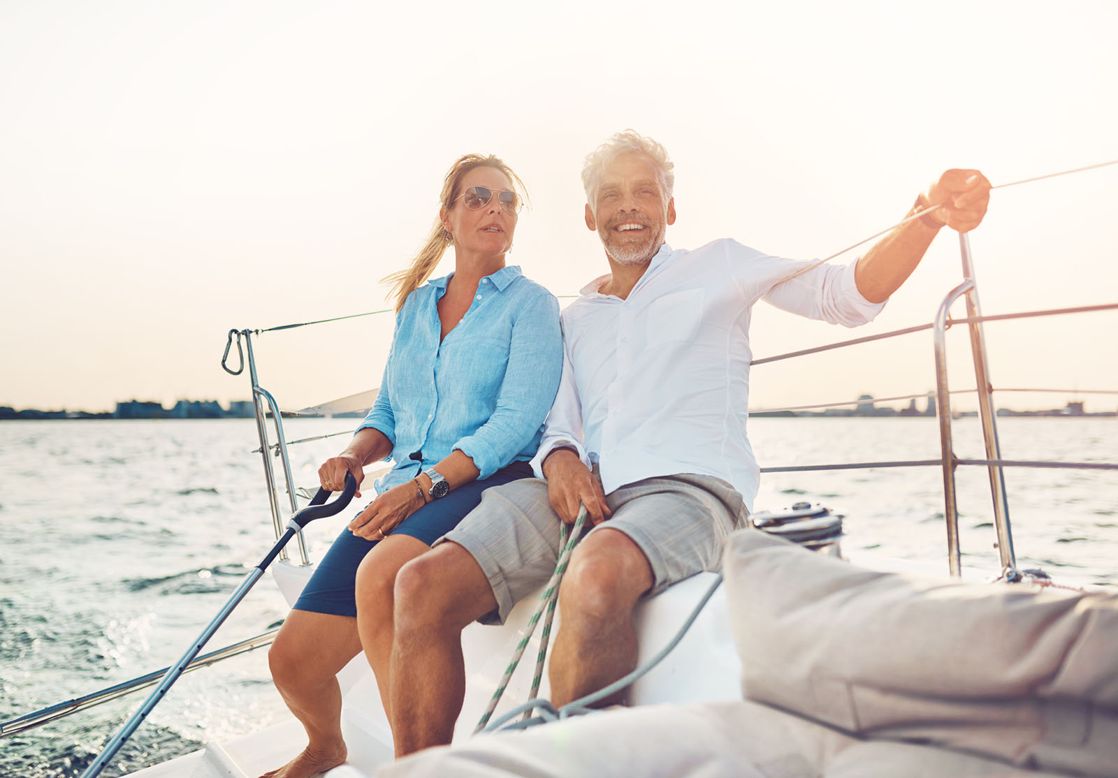 Smiling couple sailing their boat together on a sunny afternoon