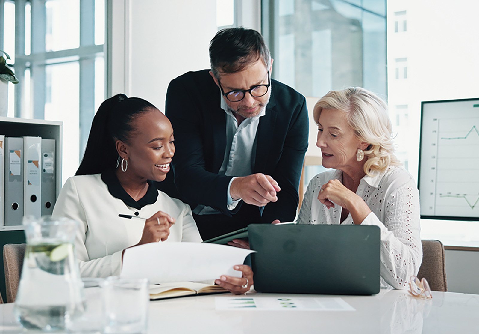 Three people looking at a laptop screen and discussing