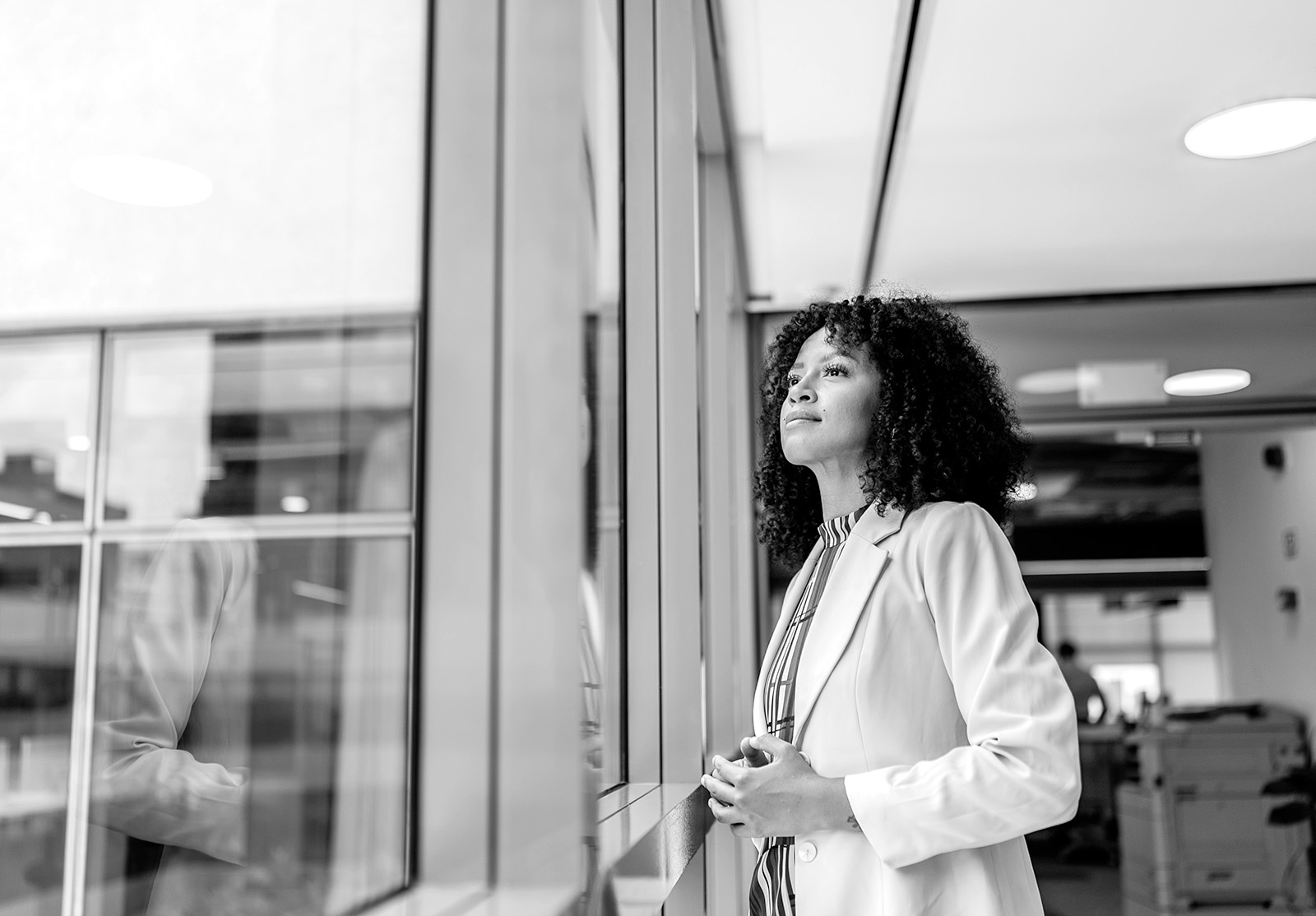 Businesswoman contemplating and looking out the window, in the office
