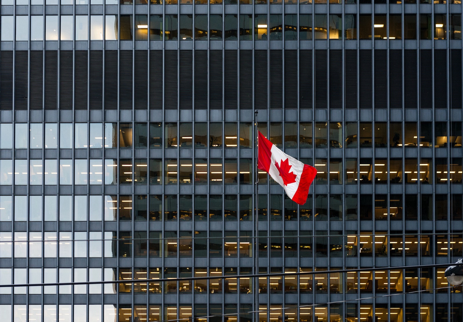 Canadian flag and modern office building in downtown Toronto alternate text for this image